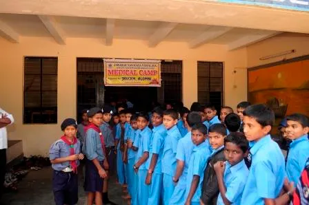 Students lined up outside a school building beneath a medical camp banner.