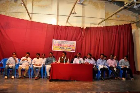A panel seated on a stage beneath the medical camp banner.